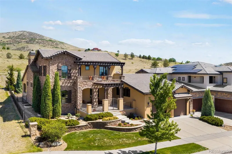 Tuscan-style stone and stucco home with terraced front landscaping and foothills behind it at 14904 W Evans Pl in Solterra, Lakewood